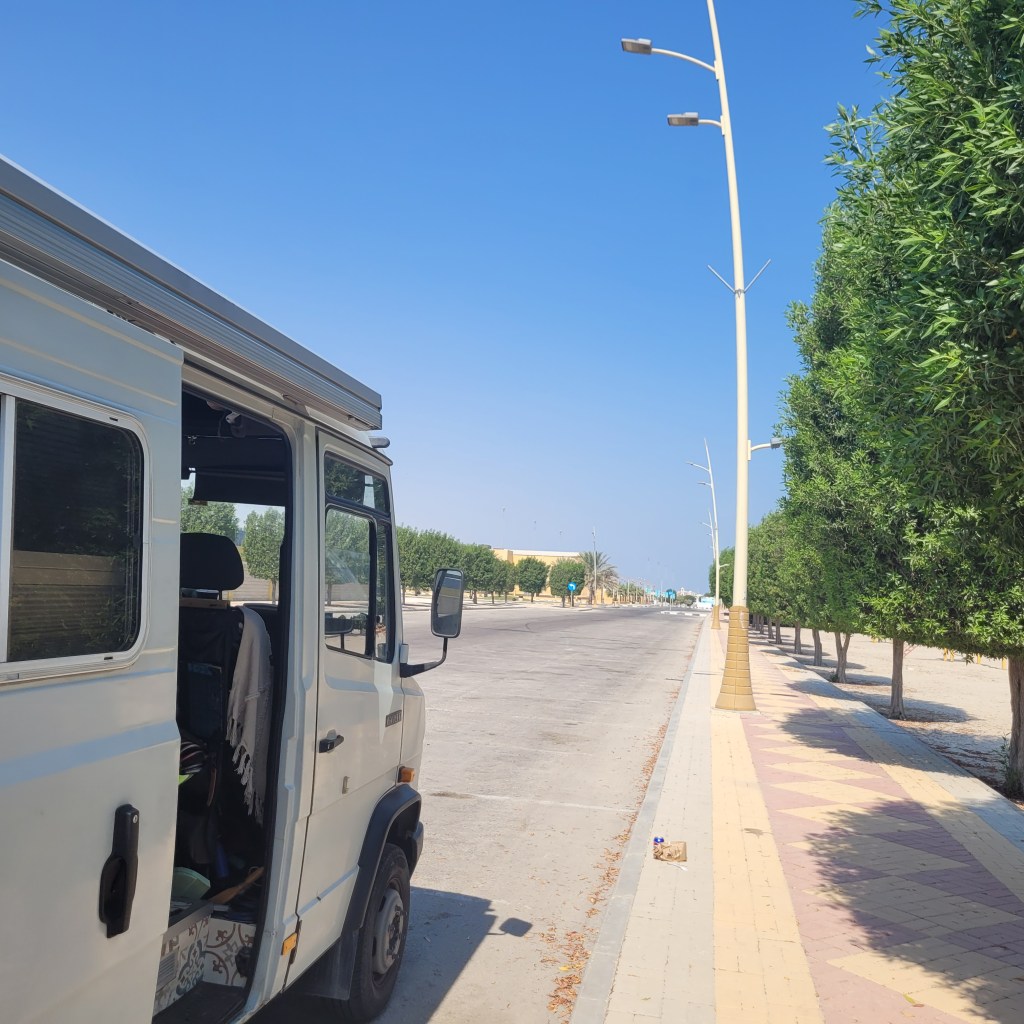Un véhicule utilitaire stationné sur une route dégagée, entouré d'arbres bien entretenus et sous un ciel bleu clair.