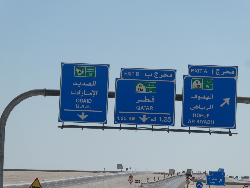 Panneau routier indiquant les directions vers les Émirats Arabes Unis, le Qatar et la ville de Hofuf en Arabie Saoudite.
