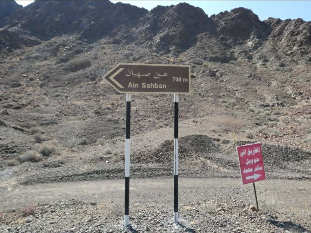 Panneau indicateur pour Ain Sahban à 700 m, situé dans un paysage montagneux aride.