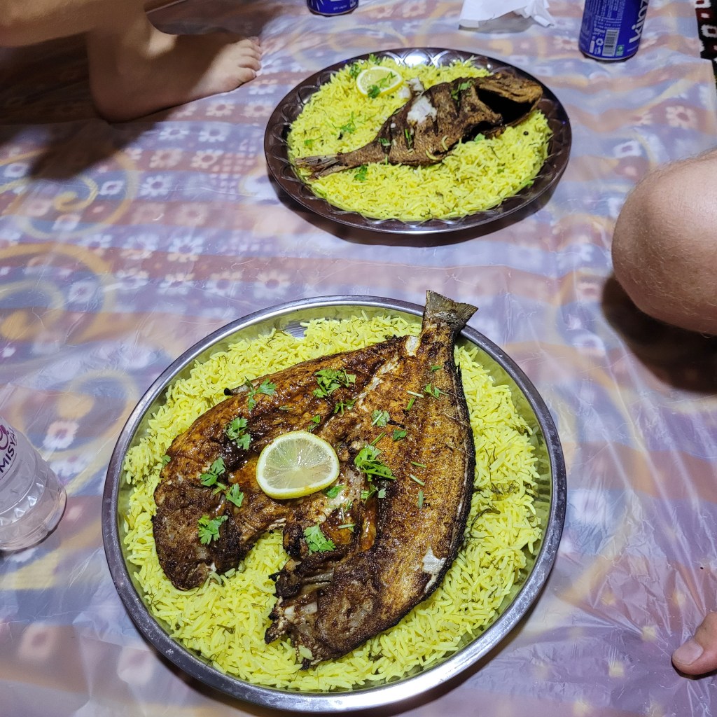 Deux plats de poisson grillé servi sur un lit de riz jaune, garnis de coriandre et de rondelles de citron.