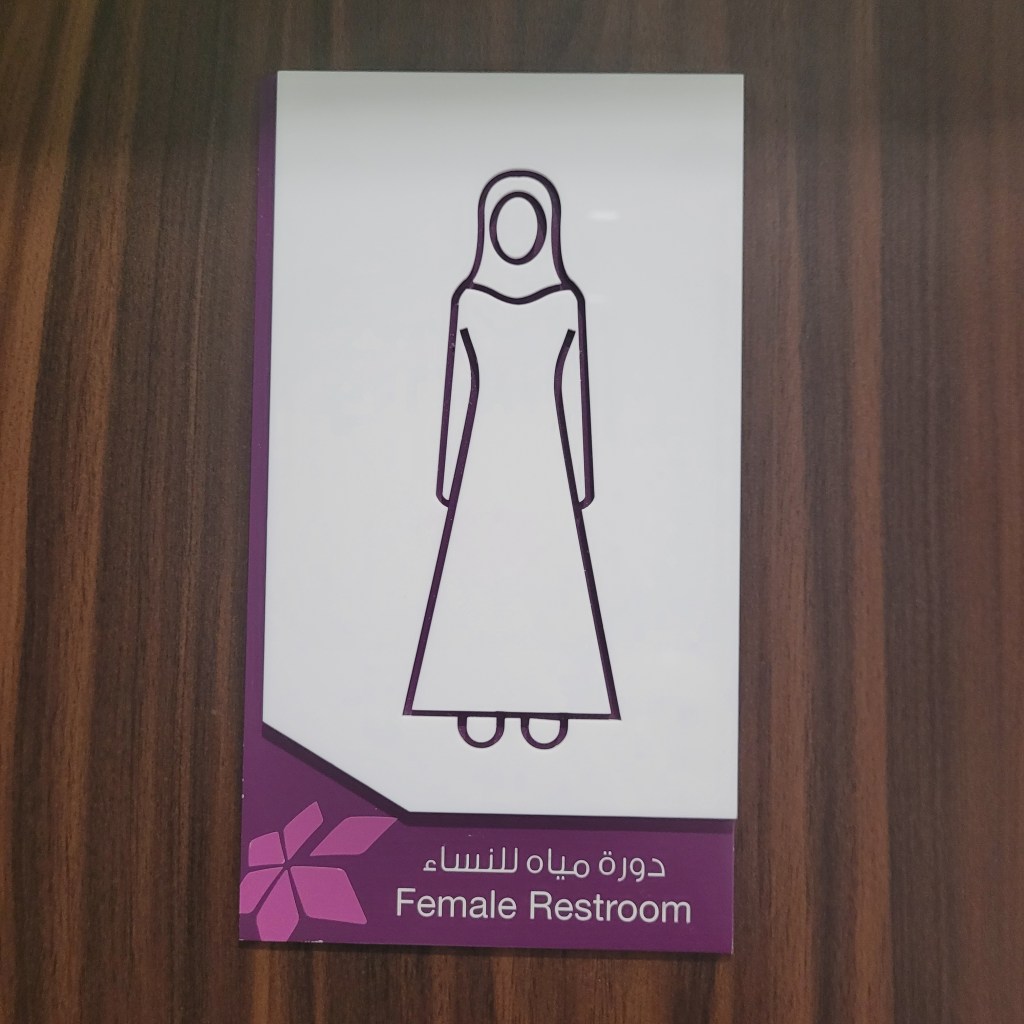 Panneau indiquant les toilettes pour femmes avec une illustration d'une femme en robe.