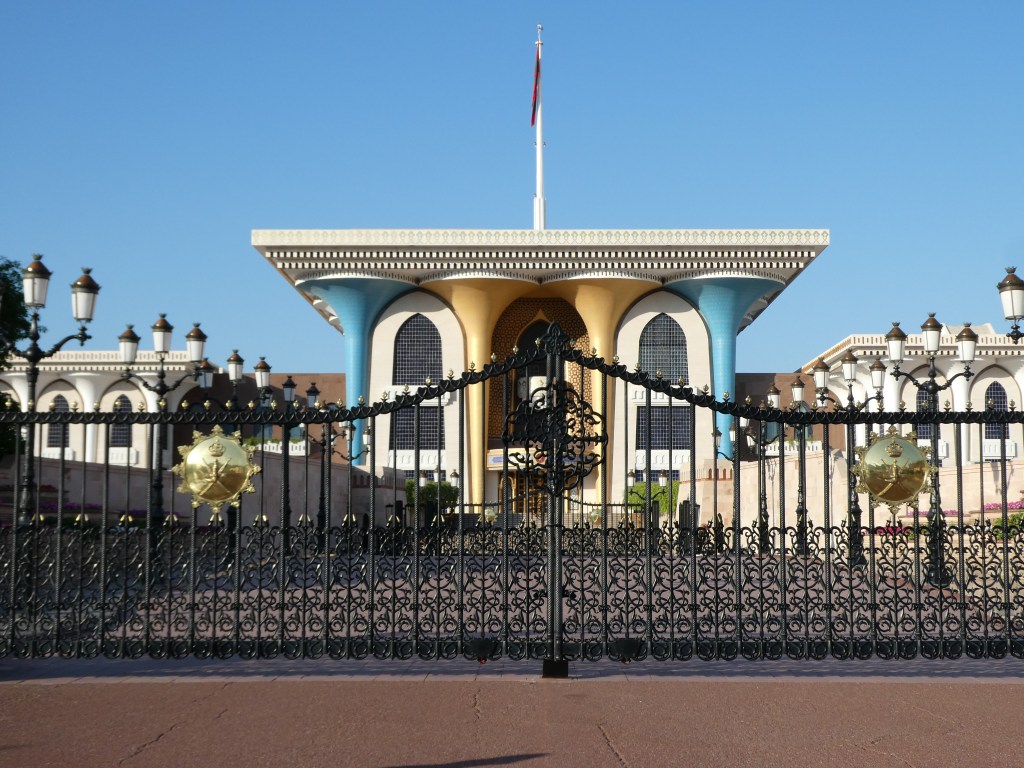 Vue du palais avec un portail en fer forgé et une coupole colorée sous un ciel bleu.