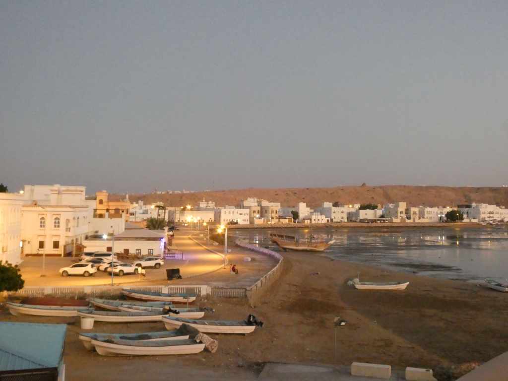Vue du port au crépuscule avec des bateaux amarrés et des bâtiments en bord de mer.