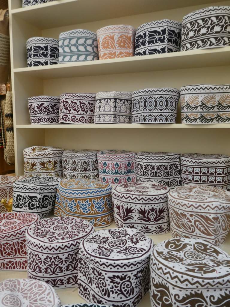 Collection de boîtes décoratives en métal, aux motifs variés et colorés, exposées sur une étagère.